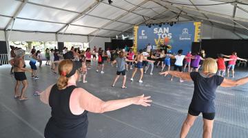 mulheres fazem alongamento sob tenda. #paratodosverem