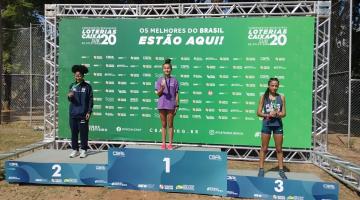 atleta de santos está no terceiro lugar do pódio, com a medalha no peito. #paratodosverem