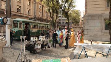 cenário de filmagem montado na praça mauá com bonde ao fundo e pessoas vestidas com roupas de época. #paratodosverem