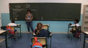 Professora está à frente de lousa e diante de alunos. #paratodosverem