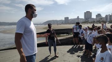 professor conversa com alunos na beira da água na praia e próximo a canal. #paratodosverem