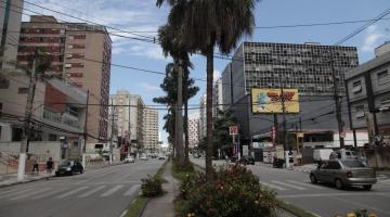 Avenida larga, com canteiro central arborizado com palmeiras, dividindo as duas pistas. #Paratodosverem