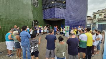 pessoas se reúnem em circulo diante de prédio. #paratodosverem 