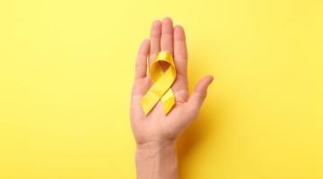 mão aberta com um laço amarelo na palma. #paratodosverem