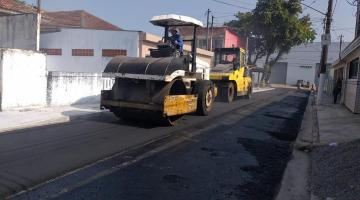 máquina compactadora passa sobre asfalto em rua. #paratodosverem 