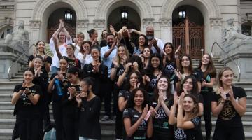 Bailarinas posam para foto na escadaria da frente da prefeitura. Elas batem palmas. #paratodosverem