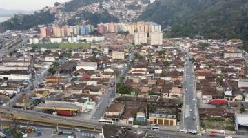 vista geral de bairro com diversas construções e morro ao fundo. #paratodosverem