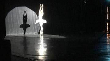 Bailarina faz solo com iluminação focada nela. #pracegover