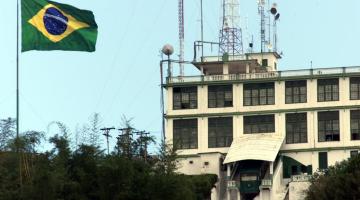 A bandeira do brasil hasteada com o prédio do antigo cassino do Monte Serrat ao lado. #Paratodosverem