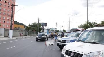 Veículos estacionados com fiscais, de costas, observando o fluxo de veículos na barreira montada no Saboó. #pracegover