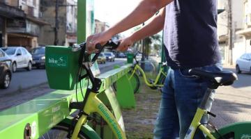 Homem segura bicicleta em uma estação do Bike Santos. #paratodosverem