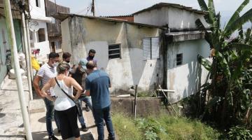 Grupo de pessoas está no alto de uma encosta ao lado de algumas casas. #Paratodosverem