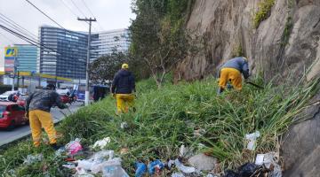 Profissionais de limpeza andam em área de mata para retirada de lixo. #pracegover