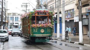 Bonde enfeitado com flores circulando em rua #paratodosverem