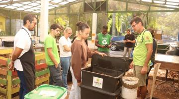 pessoas olhando mudas na semana da compostagem #paratodosverem