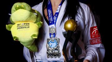 atleta segura troféu e pelúcia #paratodosverem