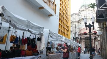 barracas de artesanato estão montadas em rua. #paratodosverem