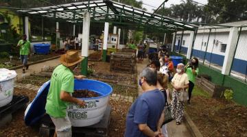 Pessoas observam profissional ensinando sobre compostagem #paratodosverem