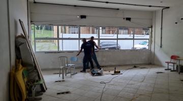dois homens trabalhando próximo a uma janela em uma sala. #paratodosverem 