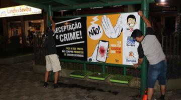 Dois jovens afixam cartaz em ponto de ônibus #paratodosverem