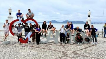 atletas em monumento com o nome da Cidade #paratodosverem