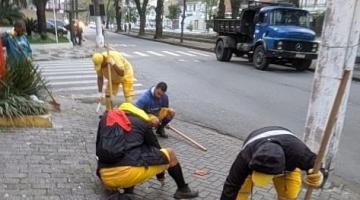 homens uniformizados raspam trecho de calçada. #paratodosverem