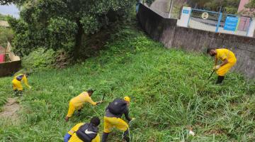Profissionais fazendo capinação em área de morro #paratodosverem