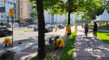 homens capinam mato do calçadão da orla. #paratodosverem 