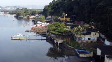 vista aérea do bairro monte cabrão, com o mar do lado esquerdo, pequenas construção em uma faixa entre o morro à direita.#paratodosverem 