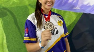 Rafaela Beatriz Silva posa para foto segurando medalha na mão direita. #paratodosverem