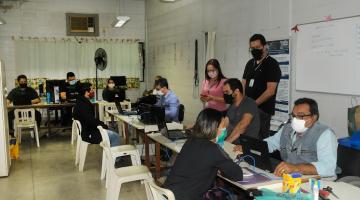 pessoas estão sentadas à mesa. De um lado, são atendentes. De outro, o público do centro de emprego. #paratodosverem 