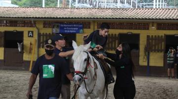 criança em cima do cavalo com pessoas acompanhando #paratodosverem