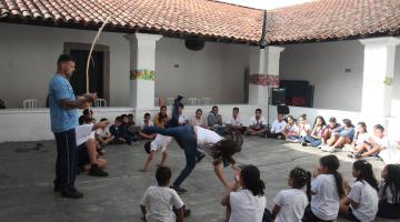 crianças jogam capoeira em quadra. #paratodosverem