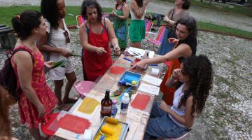 pessoas em volta de mesa com as obras #paratodosverem