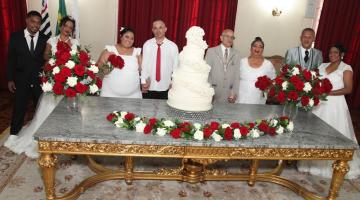 casais de noivos a caráter posam para foto atrás de mesa. #paratodosverem 