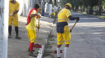 dois homens varrem rua. #paratodosverem