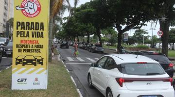 cubo em torno de posto onde se lê parada pela vida. motorismta, respeite a faixa de pedestre. Ao lado, a via com carros parados diante de uma faixa. #paratodosverem 