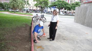homem faz um x no solo com tinta spray na área do jardim da  orla. #paratodosverem 