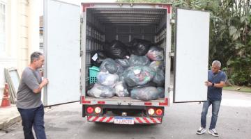 dois homens fecham portas de baú de caminhão cheio de pacotes. #paratodosverem