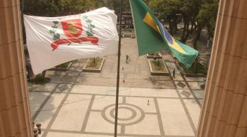 vista do piso da praça mauá da sacada da prefeitura. Em primeiro plano, as bandeiras de Santos e do Brasil tremulando e o piso ao fundo. #paratodosverem