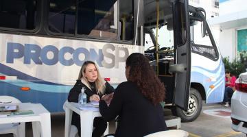 mulher diante de van do procon atende outra mulher. #paratodosverem
