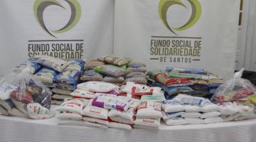 pacotes de alimentos sobre uma mesa como banner do fundo social ao fundo. #paratodosverem