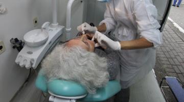 mulher está deitada em cadeira odontologica sendo atendida por uma dentista. #paratodosverem 