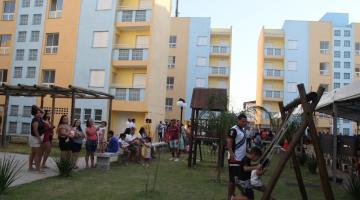 famílias na frente de conjunto habitacional #paratodosverem