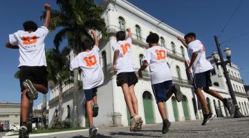 garotos com camisas 10 pulam como pelé na frente de museu #paratodosverem