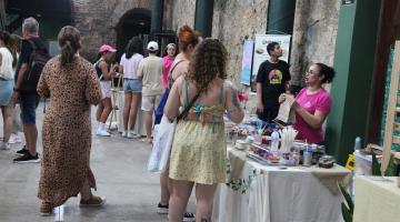 ambiente com exposicão de artesanato e pessoas circulando. #paratodosverem