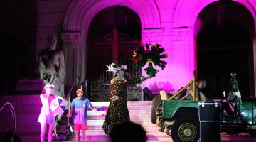 personagens se apresentam na frente de um palácio iluminado #paratodosverem