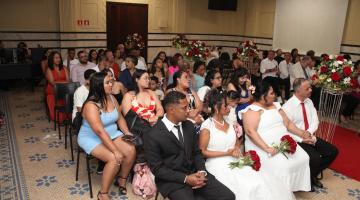 casais e convidados sentados na cerimônia do casamento comunitário #paratodosver