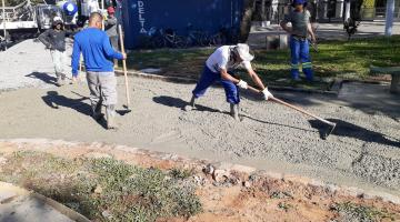 homens estão concretando passeio de praça. #paratodosverem