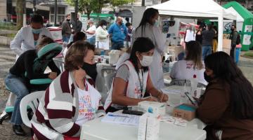 Profissionais de saúde atendem munícipe em tenda montada na praça. #pracegover